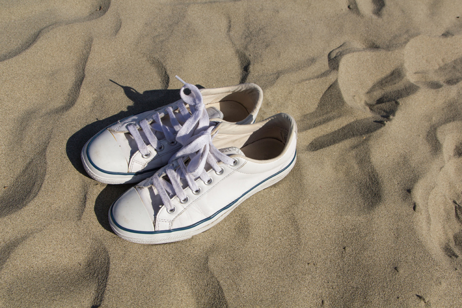 Vita sneakers på strand